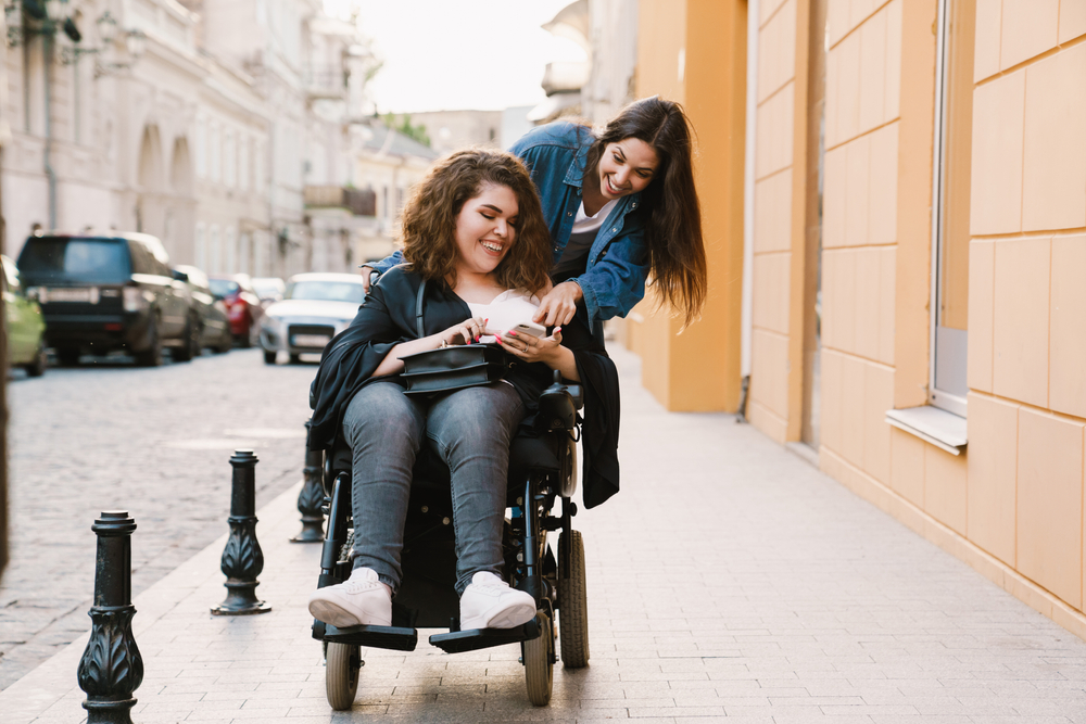 Two young women one pushing other in wheelchair
